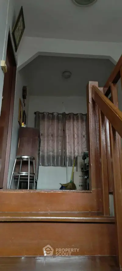 Cozy interior stairway with wooden railing and small window, perfect for homey ambiance.