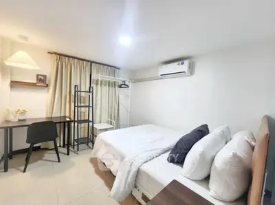 Cozy bedroom with modern decor, featuring a comfortable bed, study desk, and air conditioning.