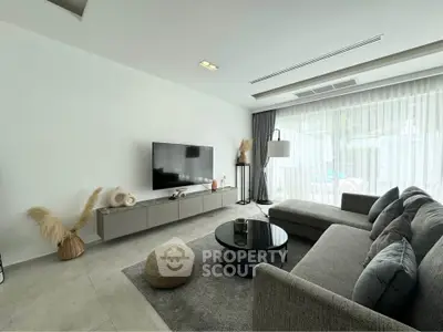 Modern living room with sleek furniture and large window offering natural light.