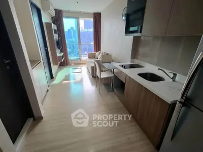 Modern apartment interior with open kitchen and city view, featuring sleek cabinetry and cozy living area.