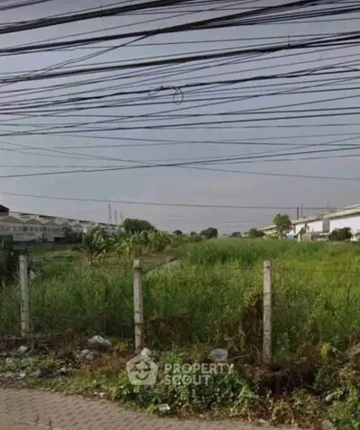Vacant land plot with potential for development in a suburban area, surrounded by greenery and residential buildings.