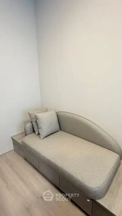 Modern minimalist living room with sleek gray sofa and light wood flooring.