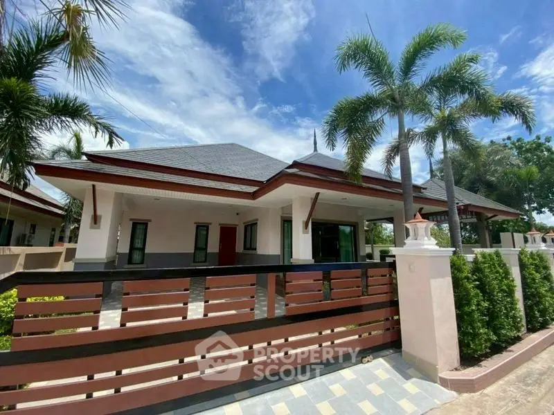Charming single-story house with modern design and lush palm trees, perfect for tropical living.