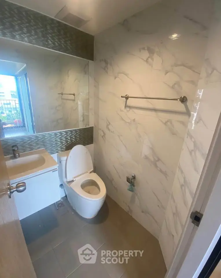 Modern bathroom with marble tiles and large mirror in a stylish apartment.