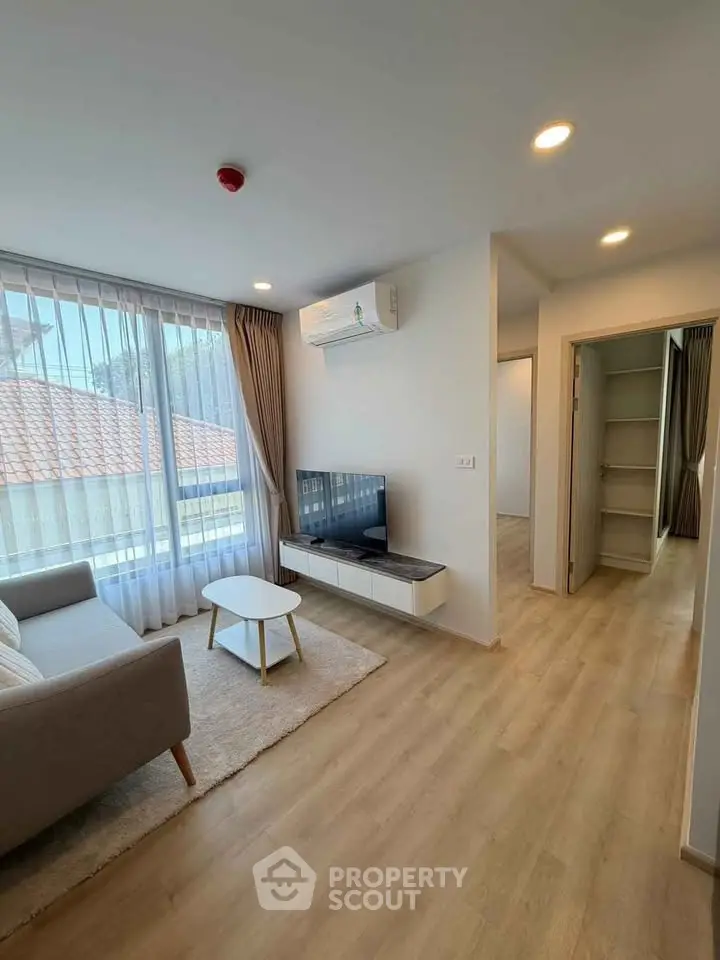 Modern living room with natural light, stylish furniture, and wooden flooring in a cozy apartment.