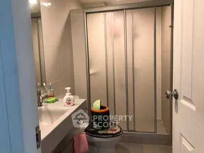 Compact bathroom with shower and sink, ideal for small apartments.