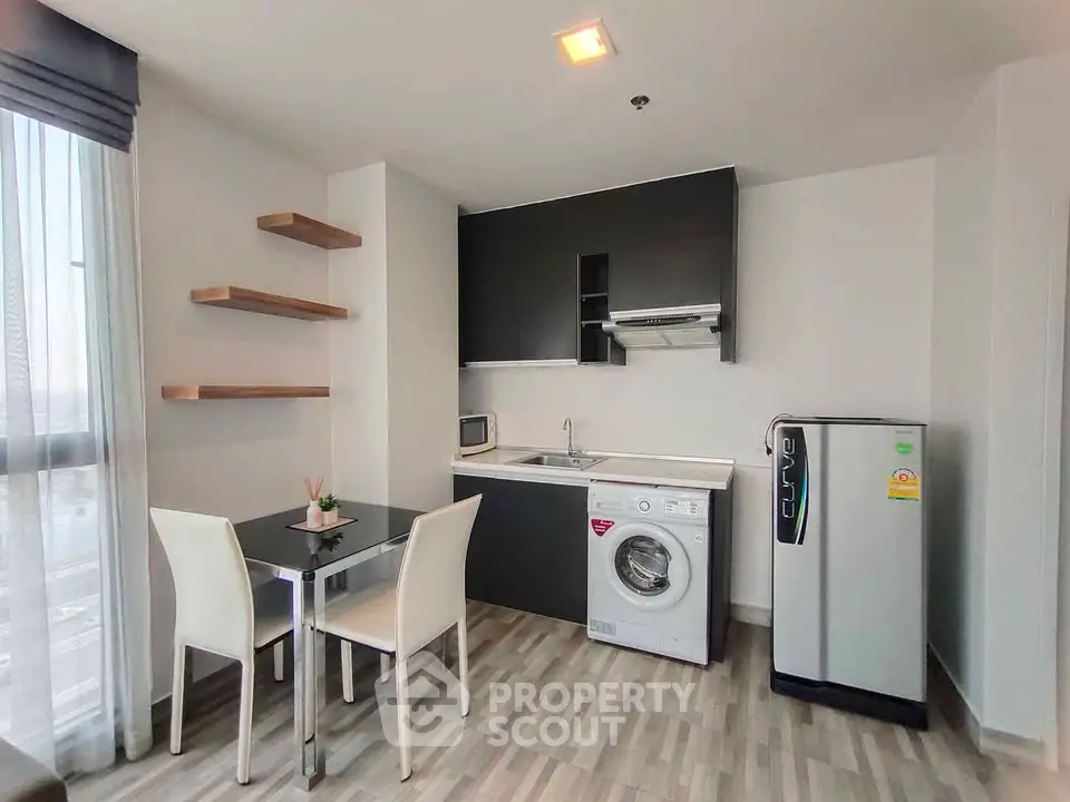 Modern kitchen with dining area, washing machine, and fridge in sleek apartment.