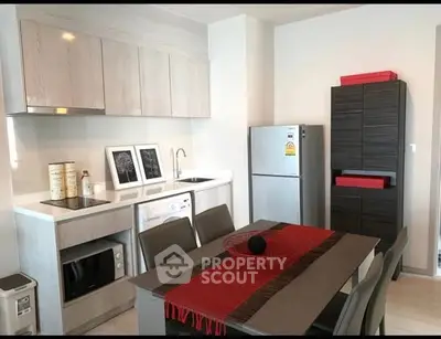 Modern kitchen with sleek cabinets, dining table, and stainless steel appliances