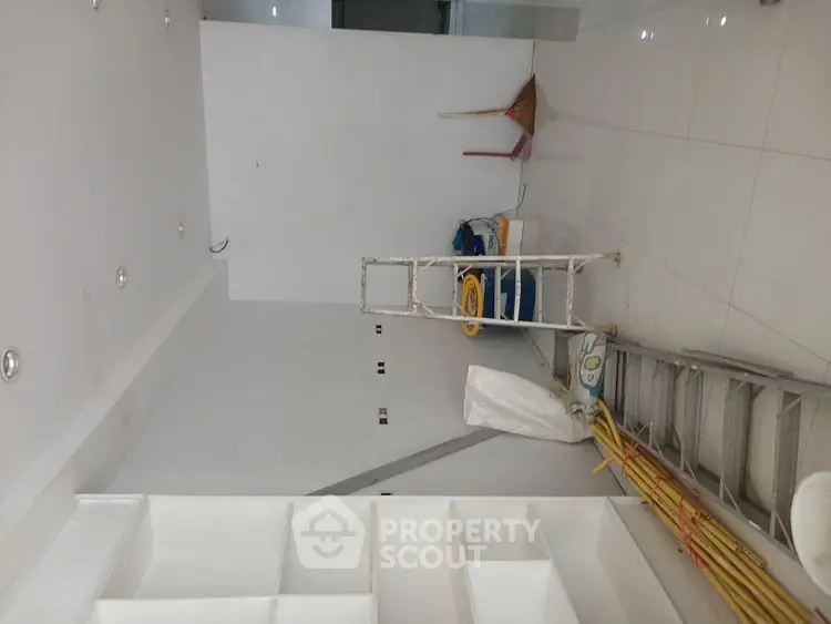 Spacious under-construction room with ladders and tools, ideal for customization.