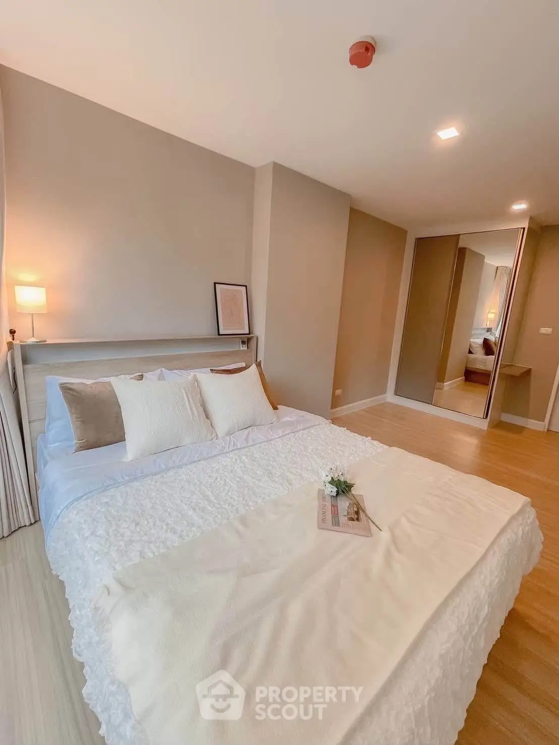 Spacious modern bedroom with cozy decor and mirrored wardrobe