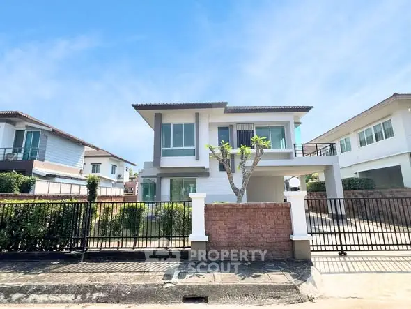 Modern two-story house with a spacious driveway and gated entrance in a suburban neighborhood.