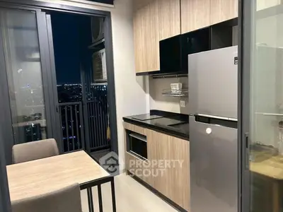 Modern kitchen with sleek cabinetry and dining area, featuring a city view from the balcony.