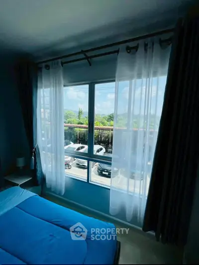 Bright bedroom with large window offering scenic view and natural light, perfect for relaxation.