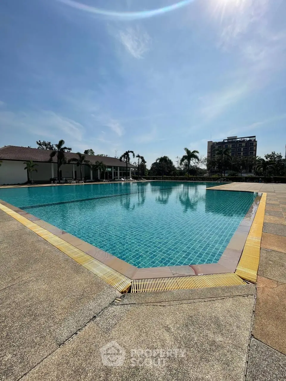 Luxurious outdoor swimming pool with clear blue water and sunny sky, perfect for relaxation and leisure.