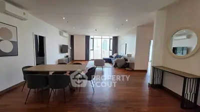 Spacious modern living room with dining area and city view, featuring elegant decor and hardwood floors.