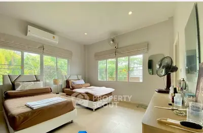 Spacious bedroom with twin beds and large windows offering lush garden views.