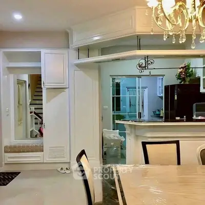 Elegant dining area with chandelier and view into modern kitchen