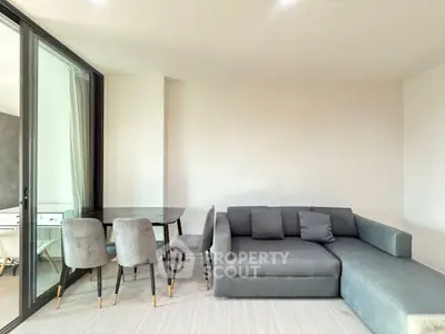 Modern living room with sleek gray sofa and dining set, featuring floor-to-ceiling windows for natural light.