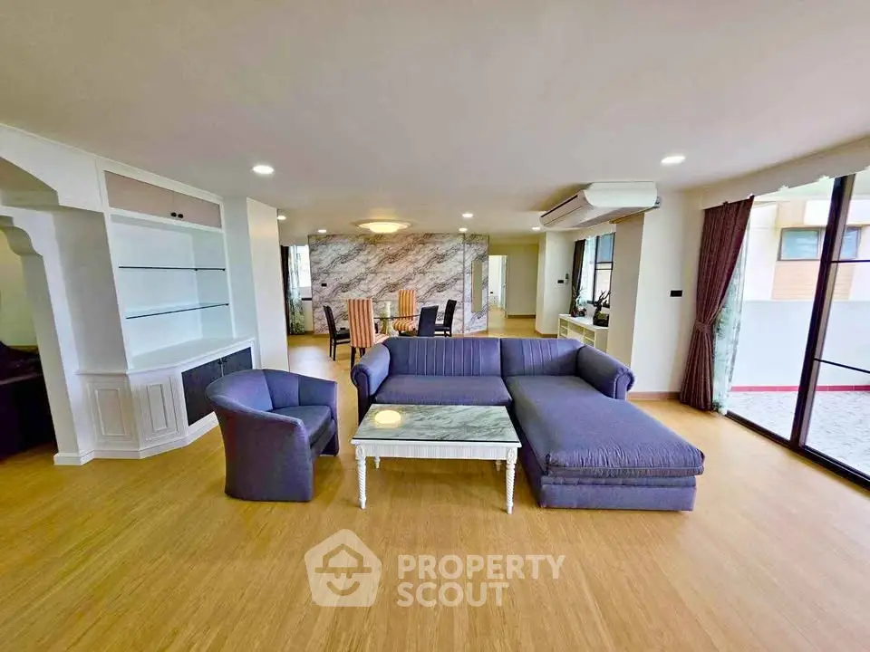 Spacious living room with modern furniture and open layout, featuring large windows and elegant decor.