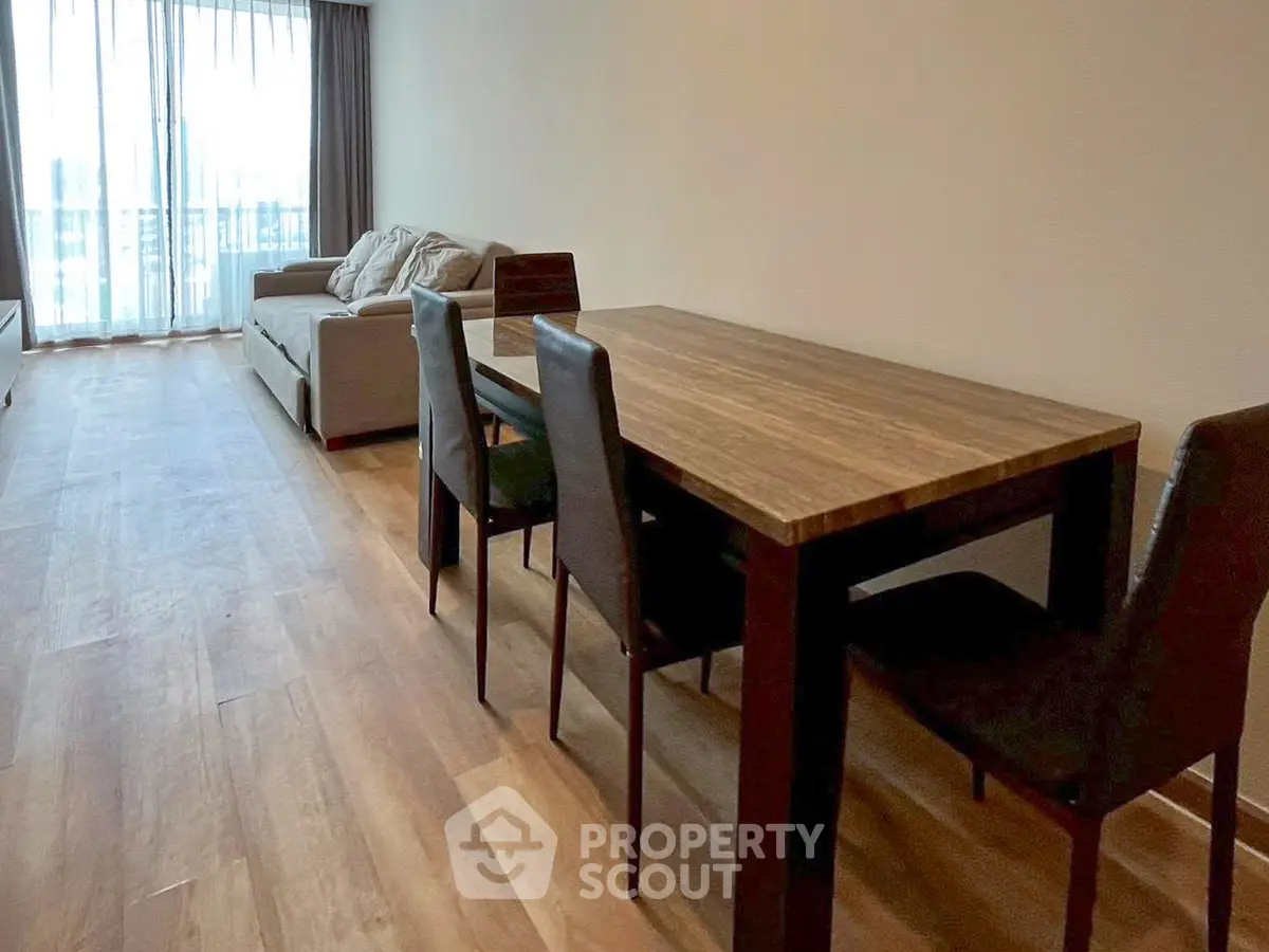 Spacious living room with wooden flooring and modern dining set, perfect for entertaining guests.