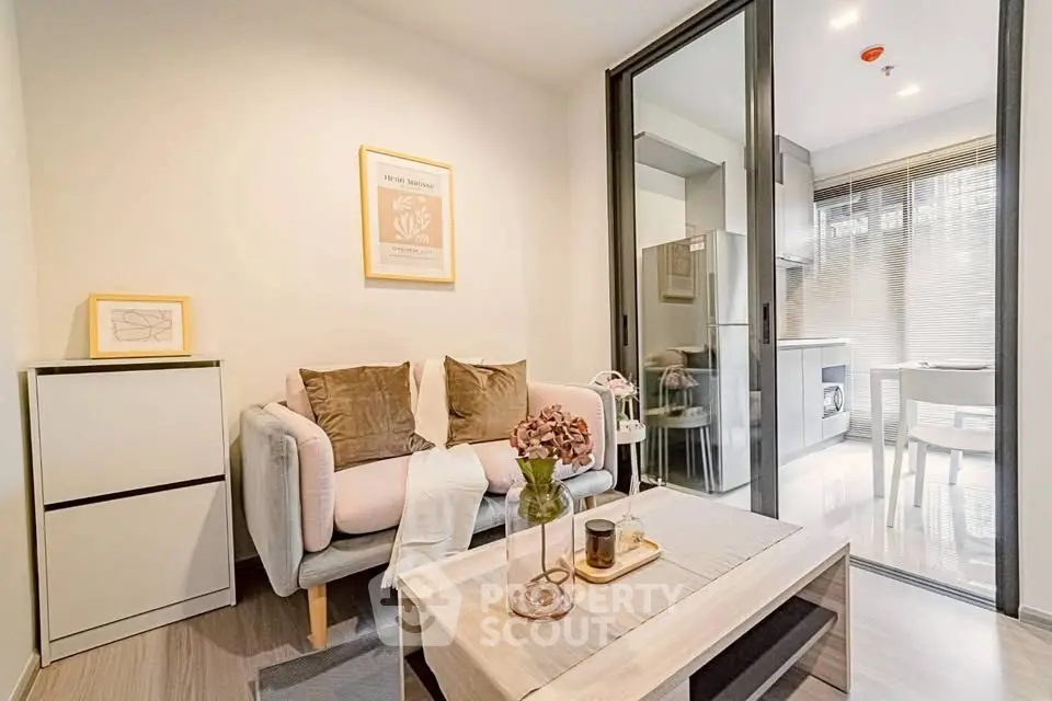 Modern living room with cozy seating and stylish decor, adjacent to a sleek kitchen area.