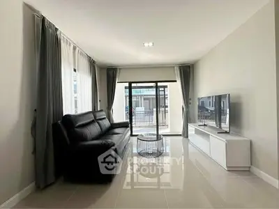 Modern living room with sleek black sofa and large TV, bright natural light from windows.