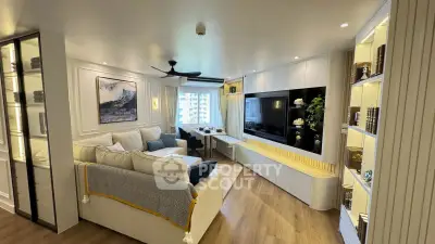 Luxurious living room with modern decor, large TV, and elegant shelving in a high-rise apartment.