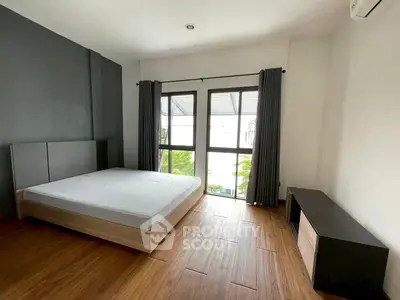 Spacious bedroom with large window and wooden flooring