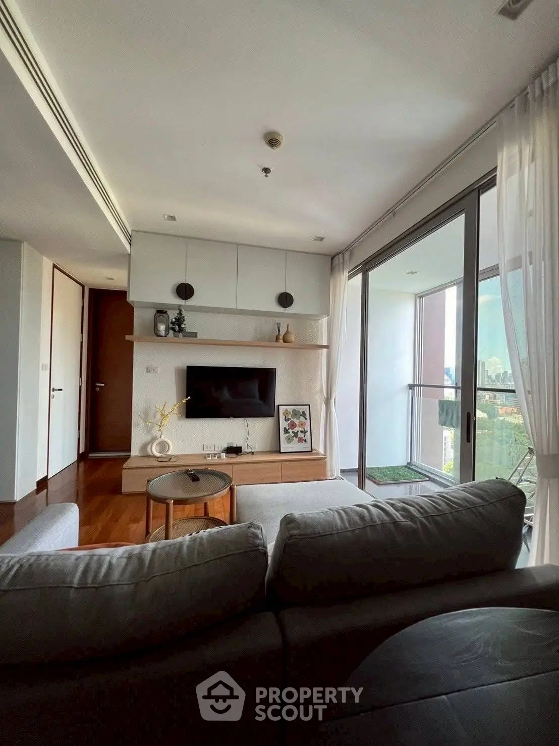 Modern living room with balcony view, featuring sleek furniture and natural light.
