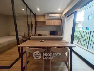 Modern studio apartment with open layout, featuring a cozy living area and balcony view.