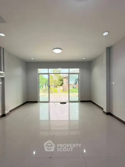 Spacious empty living room with large window and garden view, perfect for customization.