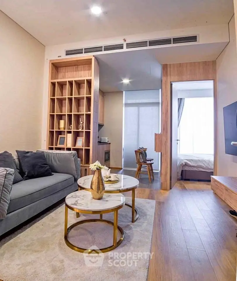 Modern living room with elegant decor and open layout leading to a cozy bedroom.