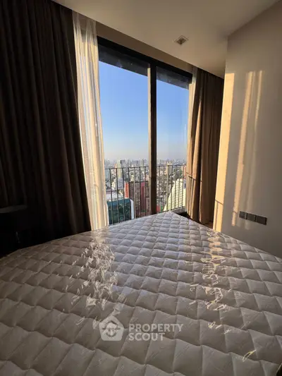Stunning bedroom with city view from a high-rise balcony, featuring elegant curtains and natural light.