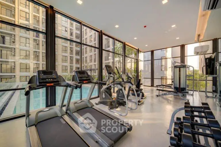 Modern gym with state-of-the-art equipment and floor-to-ceiling windows overlooking pool area.