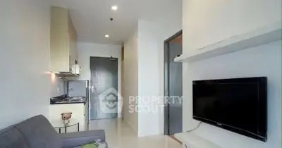 Modern living room with compact kitchen and wall-mounted TV in cozy apartment.