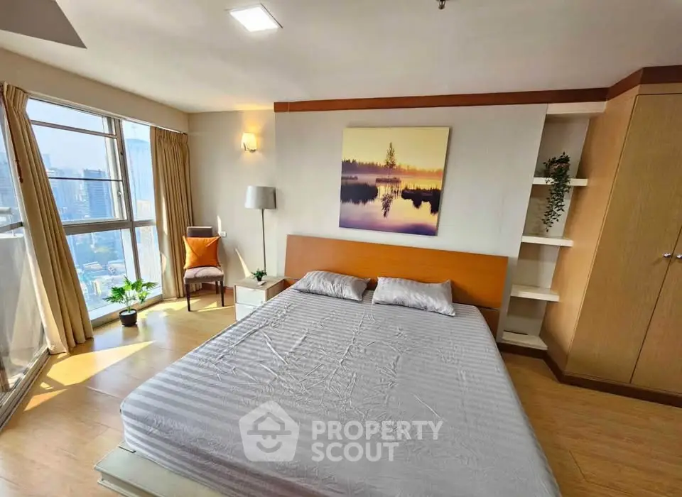 Spacious bedroom with city view, modern decor, and natural light in high-rise apartment.