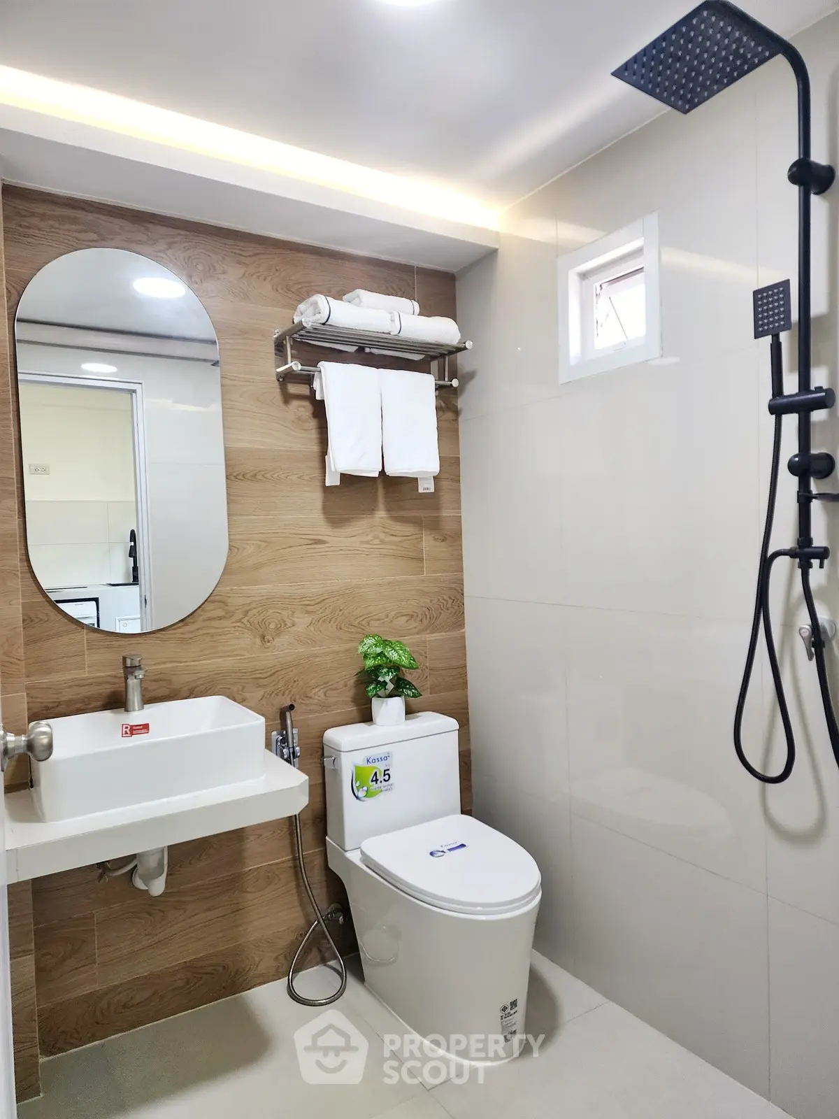 Modern bathroom with sleek fixtures and wood accents, featuring a rainfall shower and stylish mirror.