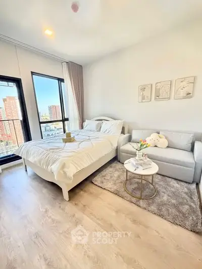 Bright and cozy bedroom with city view, featuring a comfortable bed and stylish sofa.