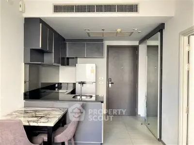 Modern kitchen with sleek cabinetry and marble dining table in a compact apartment unit.
