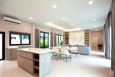 Luxurious open-plan living room with modern kitchen and elegant dining area, featuring sleek design and ample natural light.
