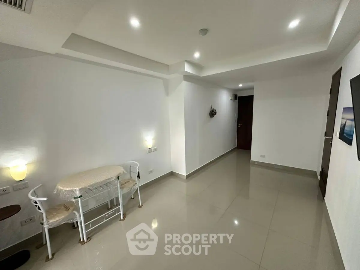 Spacious modern living room with sleek tile flooring and ambient lighting.