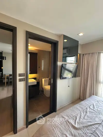 Modern bedroom with ensuite bathroom and wall-mounted TV in stylish apartment.