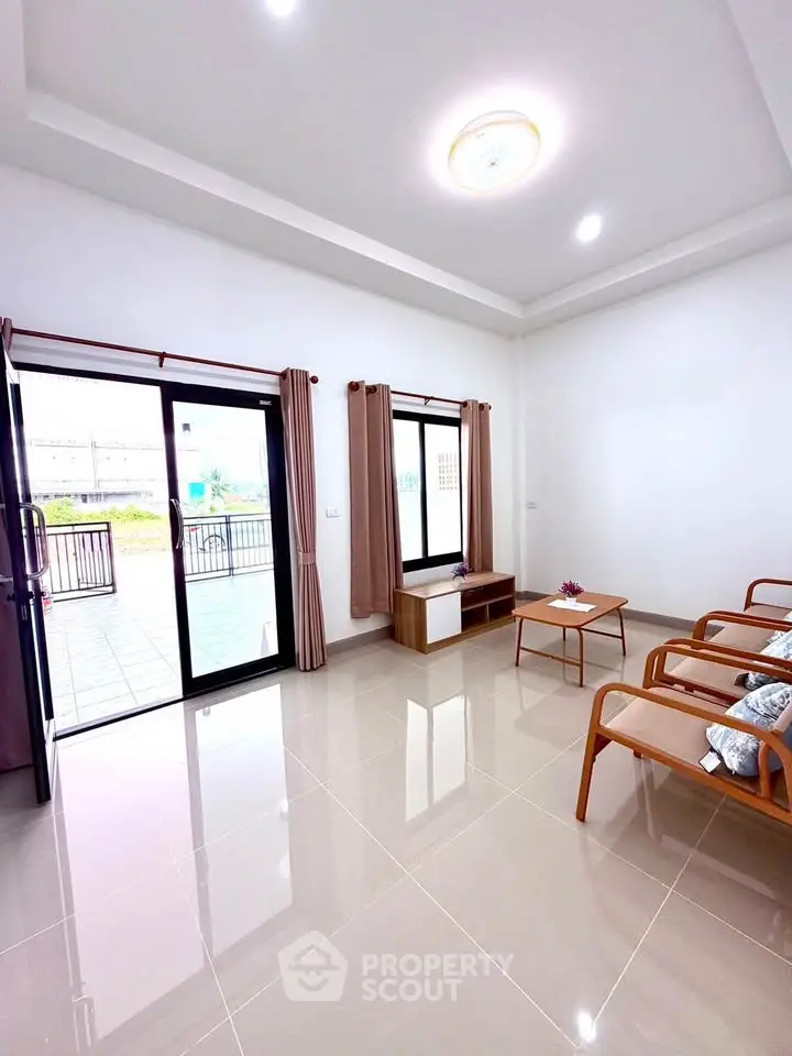 Spacious living room with modern furniture and large windows opening to a balcony, perfect for relaxation.