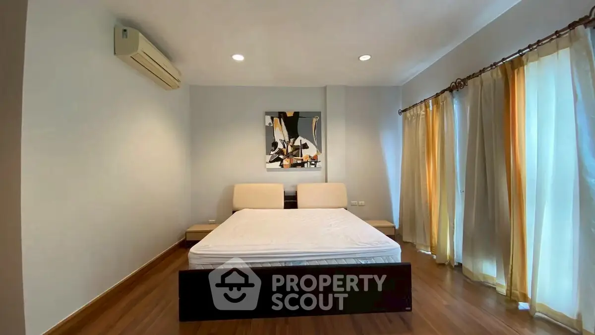 Spacious bedroom with modern decor and large windows for natural light.