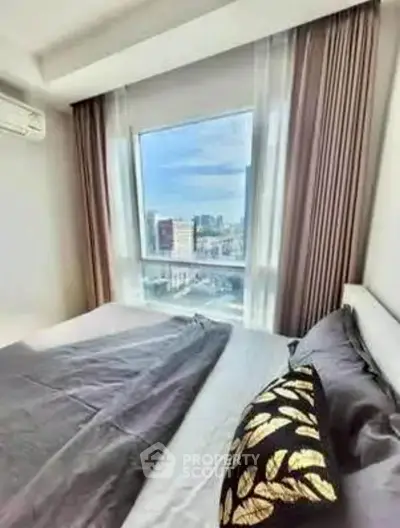 Bright bedroom with large window offering stunning city view, modern decor and cozy ambiance.