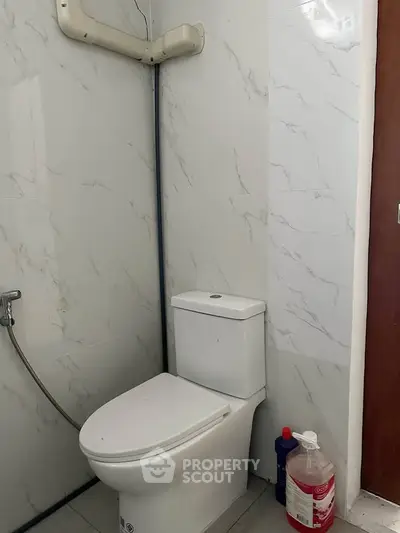 Modern bathroom with sleek white toilet and marble walls, featuring a convenient bidet spray.