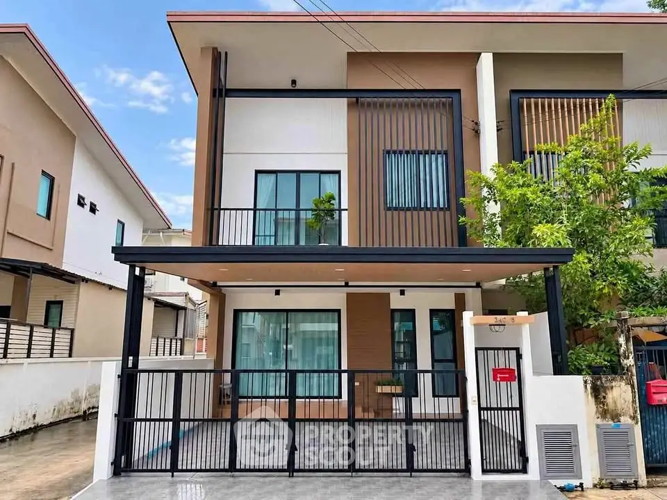 Modern two-story house with sleek design and gated entrance in a suburban neighborhood.