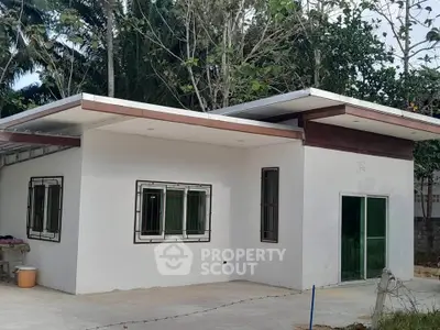 Modern single-story house with unique roof design and large windows in a lush setting.
