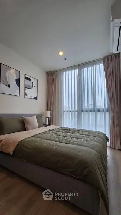 Spacious bedroom with modern decor and large windows offering natural light.
