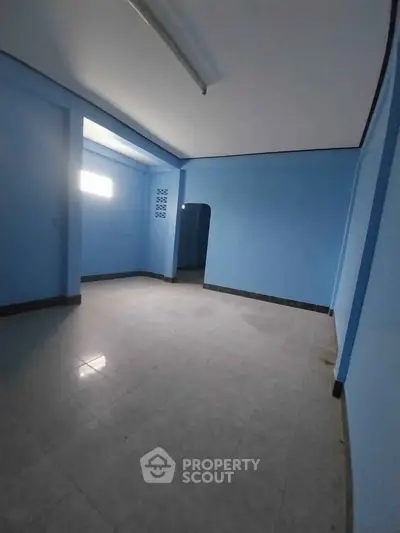 Spacious blue-walled room with tiled flooring, ideal for versatile interior design opportunities.